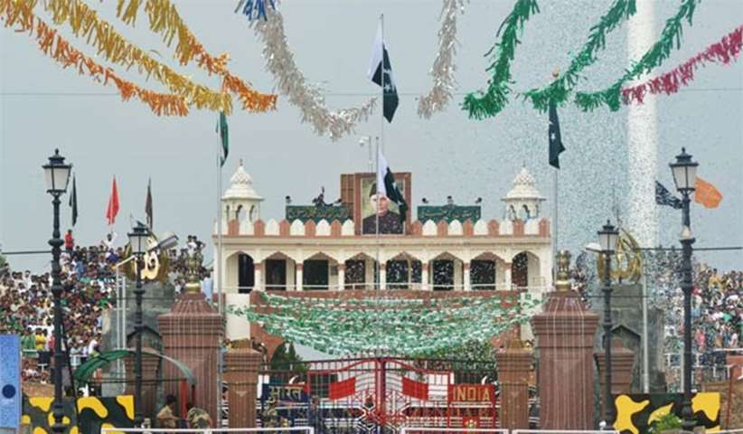 A Pakistani Ranger unfurls the national flag as people watch a ceremony at the Wagah border post