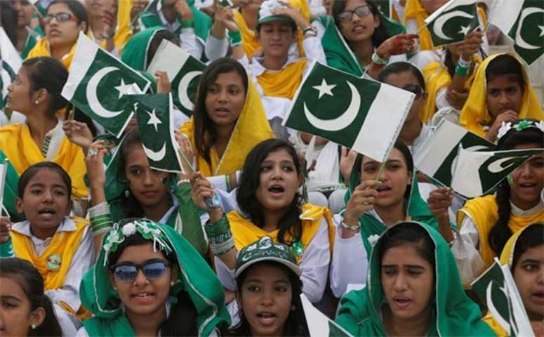 Students wave Pakistan\'s national flag while singing patriotic songs in Karachi