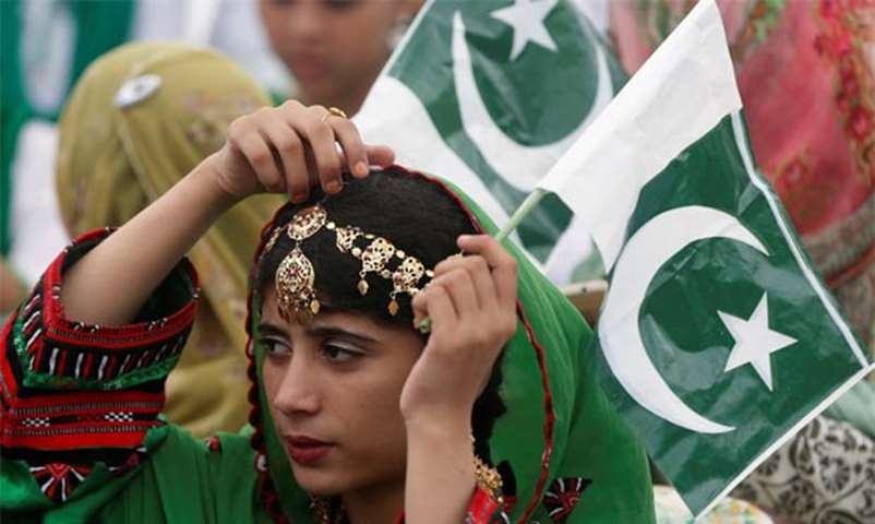 A girl holds a national flag as she attends an Independence Day ceremony in Karachi on Monday