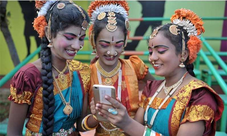 Indian girls look at a mobile phone prior to taking part in celebrations in Secunderabad on Tuesday