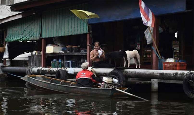 A man living on the canal thanking the postman for delivering his mail in Bang Khun Thian district