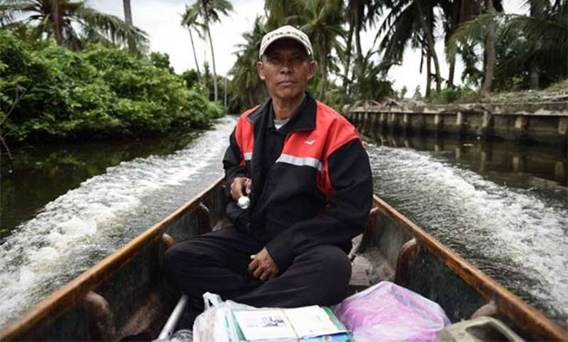 Nopadol Choihirun steering his boat through the canal on the outskirts of Bangkok