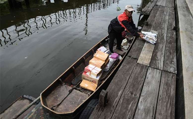The Thai postman loading parcels and mail into a boat on the canal