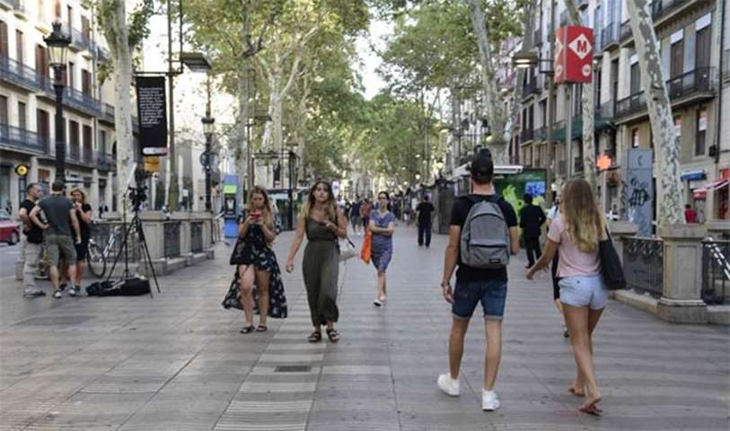 Tourists and residents walk on the Rambla boulevard the morning after a vehicle attack