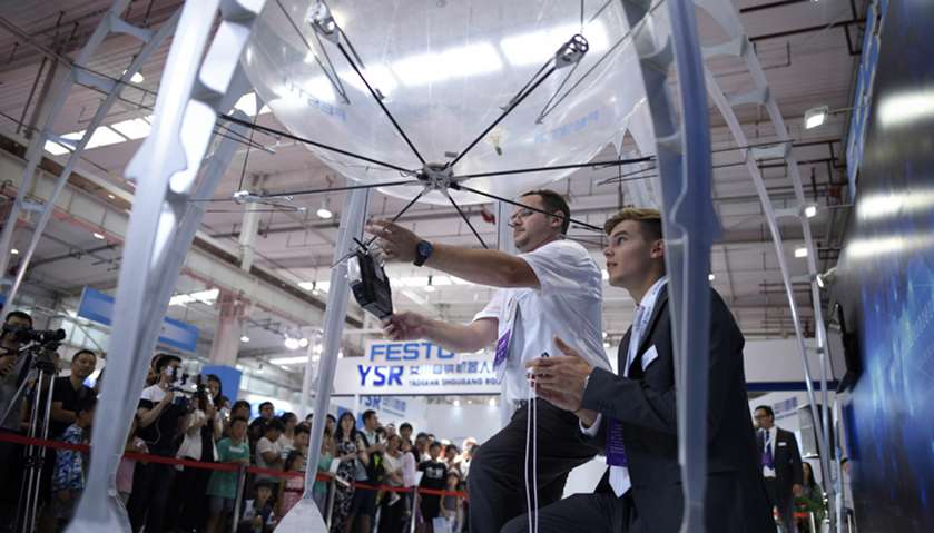 Staff members of Festo withdraw a flying object at the 2017 World Robot Conference in Beijing