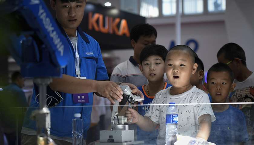 A boy controls a robot arm at the 2017 World Robot Conference in Beijing