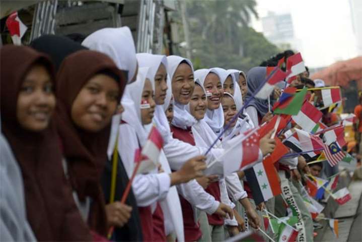 Indonesian students wave flags as they watch the torch relay