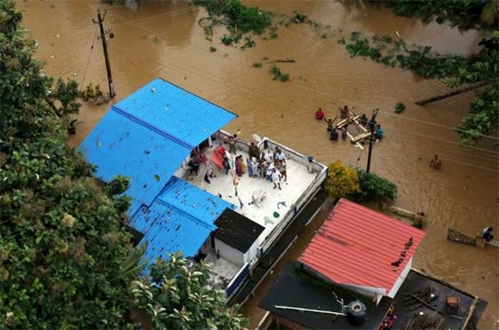 People wait for aid on the roof of their house in the southern state