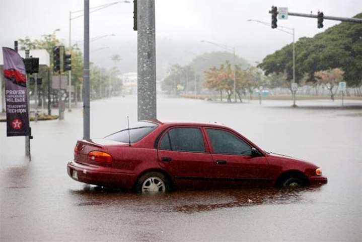 Rain falls on a car partially submerged in floodwater from Hurricane Lane in Hilo, Hawaii