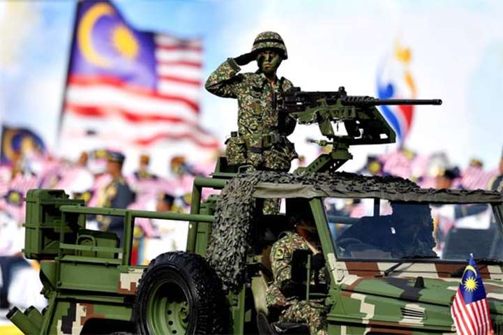 A Malaysian soldier salutes from an armoured vehicle during the parade