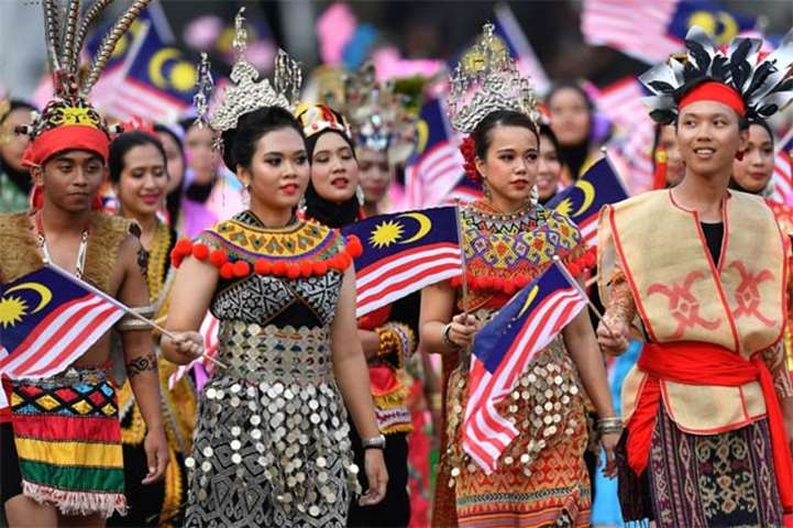 Malaysian schoolchildren dressed in traditional outfits march during the National Day parade