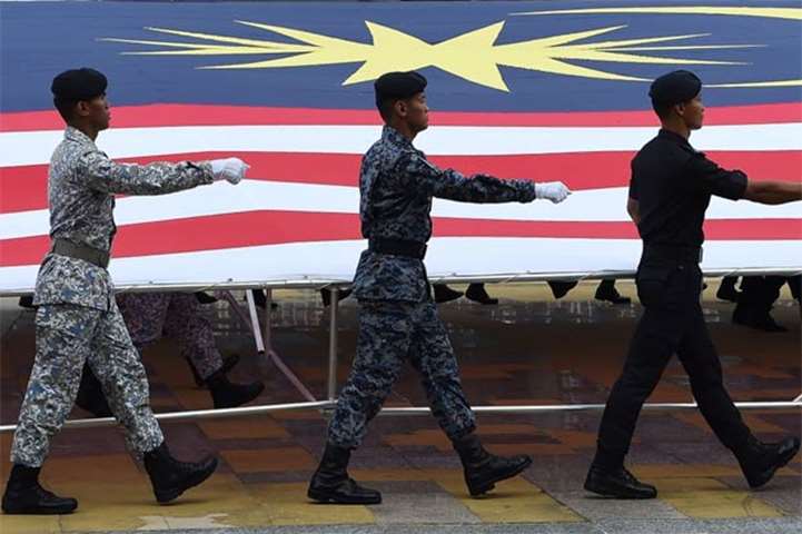 Malaysian Armed Forces personnel carry a huge national flag as they march in Putrajaya