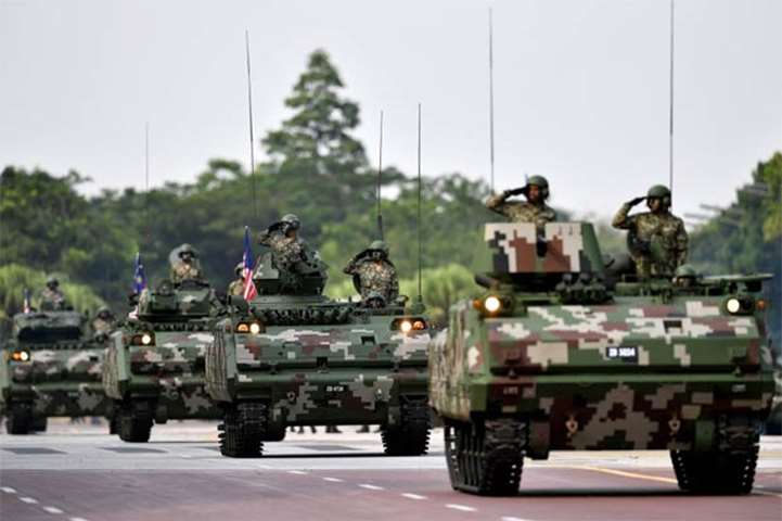 Malaysian soldiers salute from their armoured vehicles during the National Day celebration