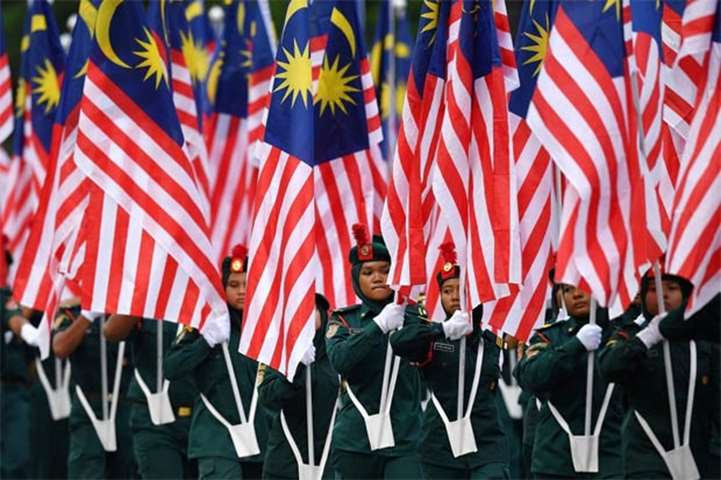 Malaysian school cadets carry national flags during the National Day parade in Putrajaya on Friday