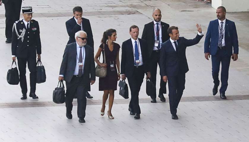 French President Emmanuel Macron waves to people as he walks towards a series of meetings in Biarrit