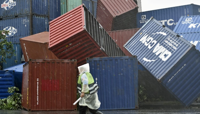 A man walks past downed shipping containers at the Kaohsiung Harbour