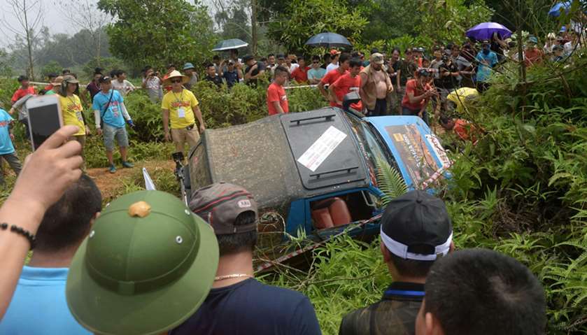 Spectators looking at a vehicle that fell on its side while taking part in the Vietnam Offroad 2017 