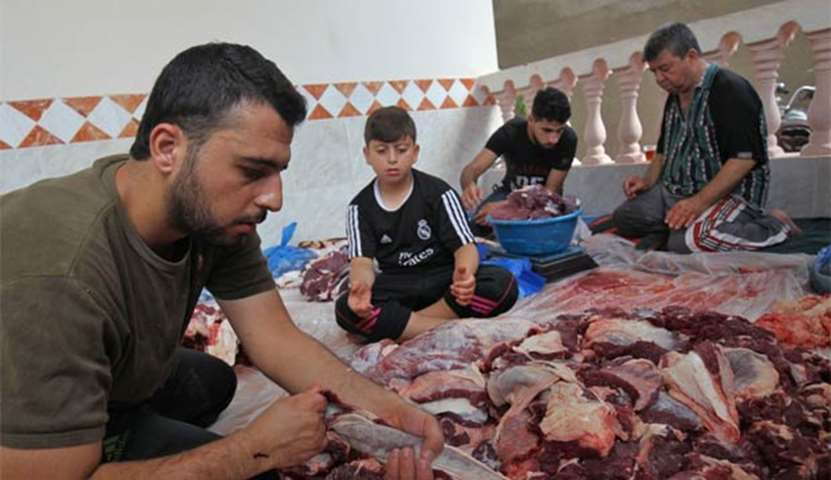 Palestinian men divide meat after slaughtering a bull in Rafah in the southern Gaza Strip