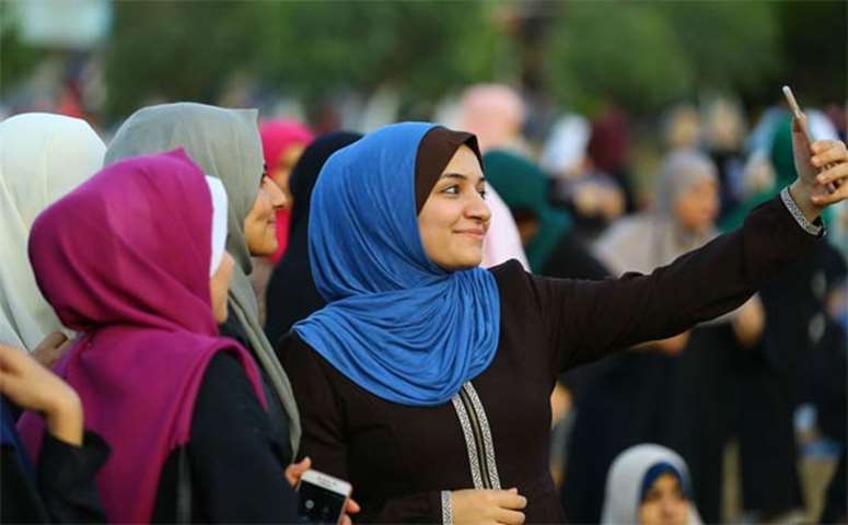 A Palestinian woman takes a selfie while celebrating in Gaza City after performing the Eid prayer