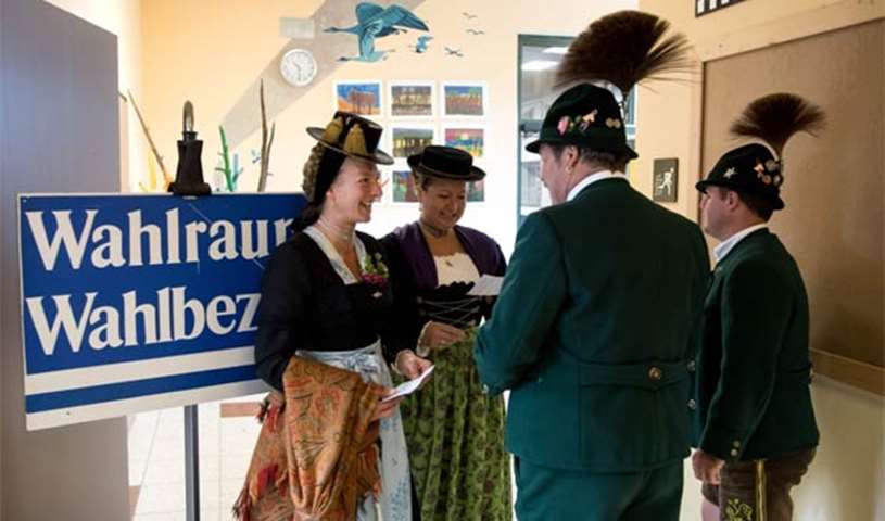 Voters in traditional Bavarian dresses stand at a polling station in Unterwoessen near Rosenheim