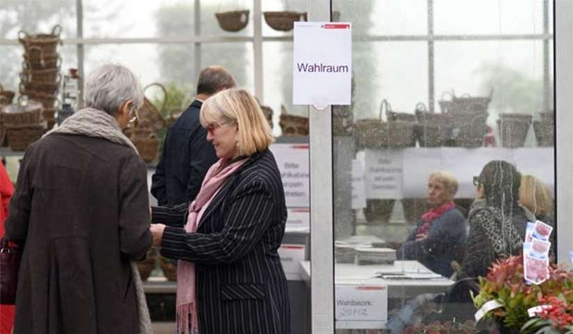 Voters wait to cast their ballots at a polling station installed in a gardening centre in Cologne