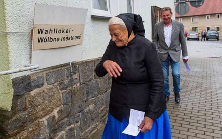A woman wearing traditional Sorb clothing goes into a polling station in Crostwitz, eastern Germany