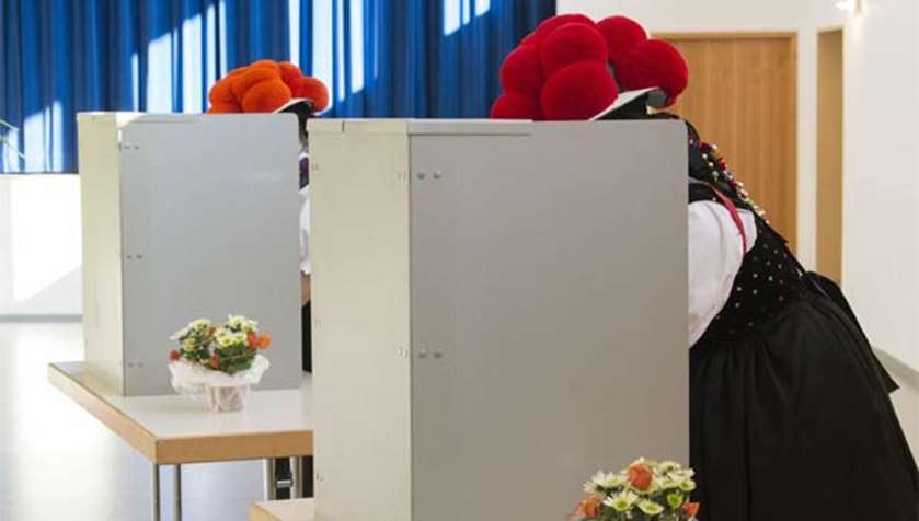 Women wearing ‘Bollenhut’ pompon hats fill out their ballot papers in Gutach near Freiburg