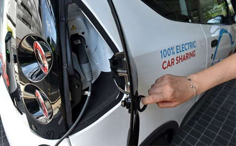 A staff member displays the charging compartment of an electric Bluecar