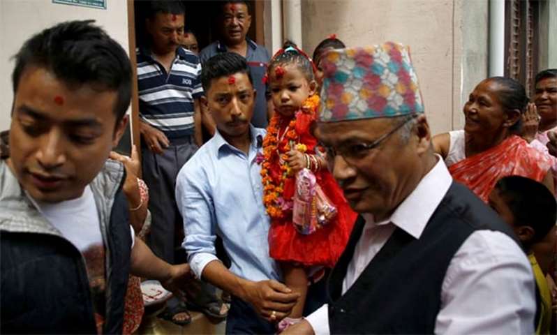 Trishna Shakya is carried by her father as they head towards the Kumari House in Kathmandu