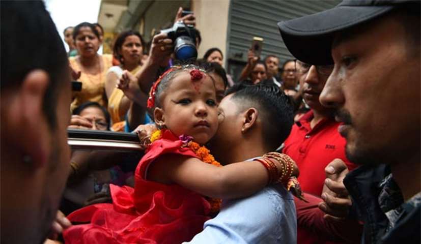 Trishna Shakya is carried by her father Bijaya Ratna Shakya as she leaves her home for Kumari House