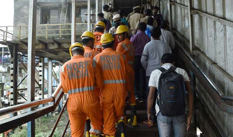 Indian rescue personnel walk through the scene of a stampede on a railway bridge in Mumbai on Friday