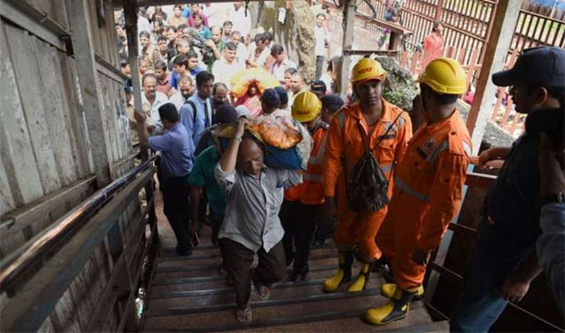 Rescue personnel and commuters walk on a railway bridge in Mumbai which was the scene of a stampede