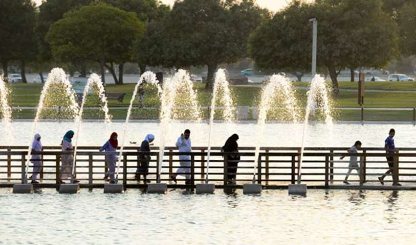 People walk through the artificial lake at Aspire Park