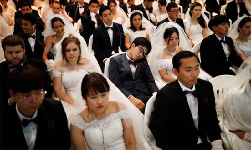 A groom takes a nap as newlywed couples attend a ceremony at Cheongshim Peace World Centre
