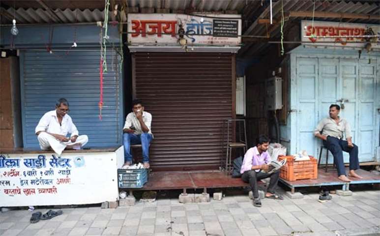 Shopkeepers sit outside their shops at a market in Mumbai during a nationwide general strike