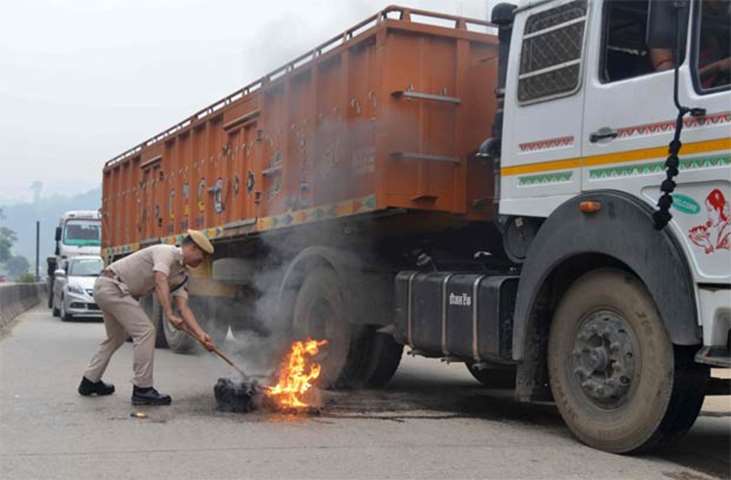 An Indian policeman removes a burning a tyre set alight along a national highway in Guwahati