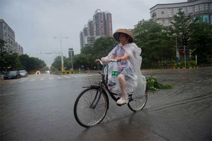 A woman cycles through flooded streets after Typhoon Mangkhut hit Yangjiang, Guangdong province