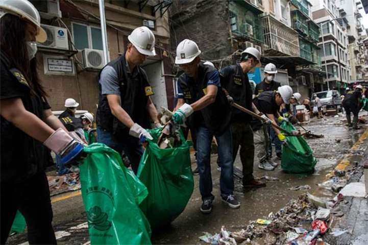 Police clear rubbish and debris from a street in Macau on Monday