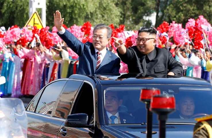 South Korean President Moon Jae-in and North Korean leader Kim Jong Un wave during a car parade