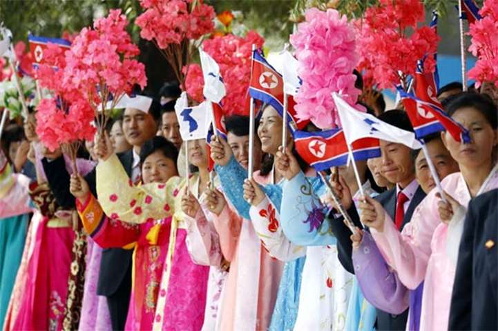 Pyongyang citizens wave bouquets as they watch a car parade on Tuesday