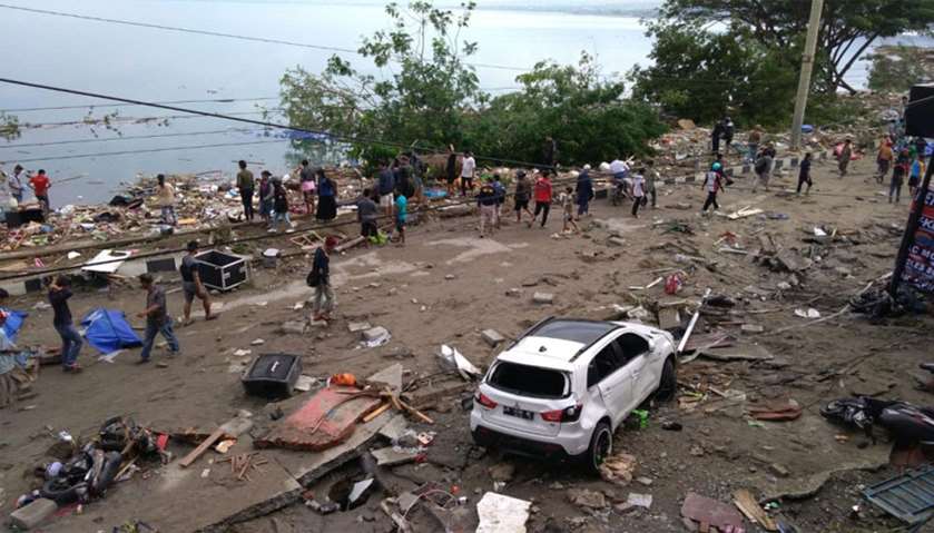 People walk past a day after an earthquake and a tsunami hit Palu, on Sulawesi island