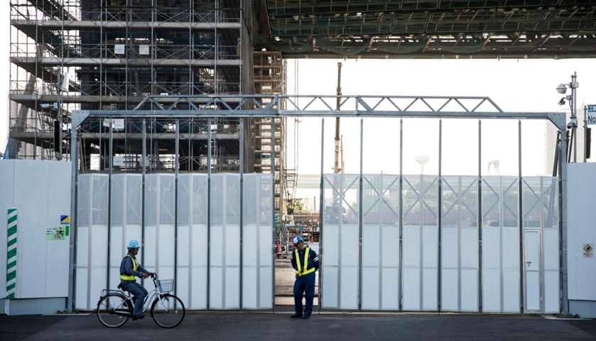 A Japanese worker rides a bicycle outside the construction site of the Olympic Aquatics Centre