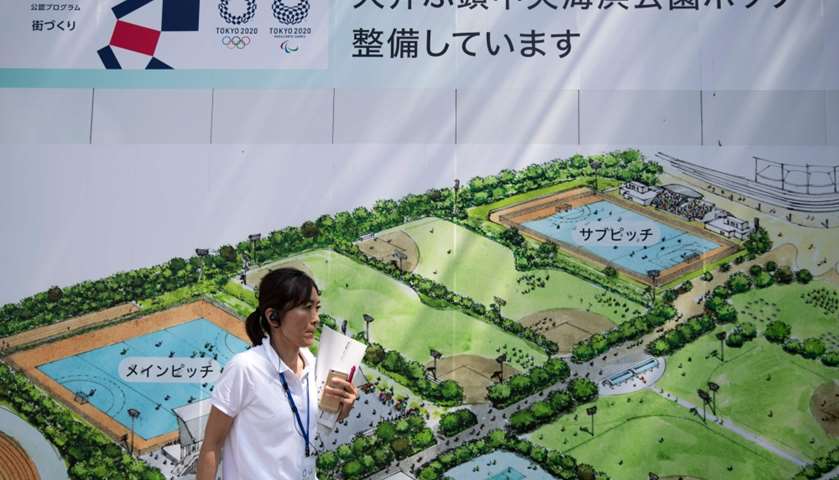 A staff member of the organising committee stands next to a map of hockey complex at Seaside Park