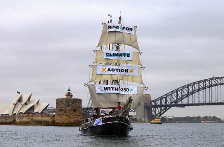 A tall ship displaying banners sails on Sydney Harbour as part of global climate change protests