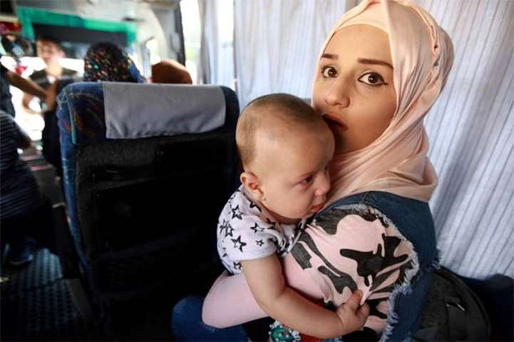 A Syrian woman holds a toddler in her arms inside a bus as refugees leave Beirut