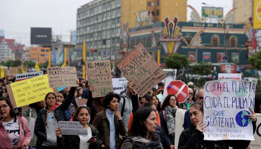 People hold placards during a Global Climate Strike rally in Lima, Peru