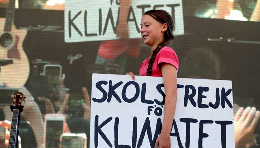 Swedish climate activist Greta Thunberg carries a sign onto the stage at the Global Climate Strike i