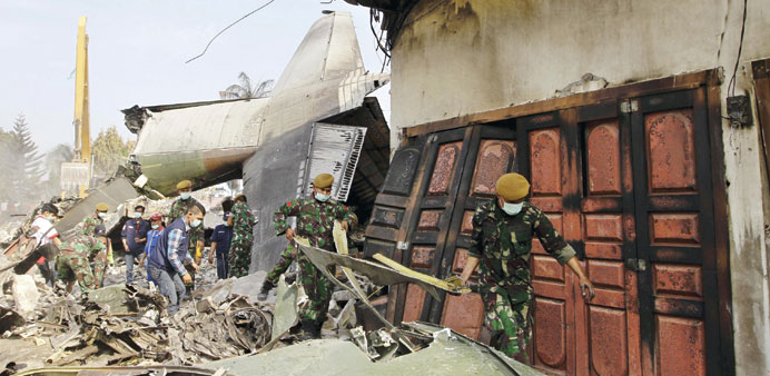 Indonesian soldiers remove debris from the site of a military C-130 transport plane which crashed yesterday into a residential area of Medan, North Su