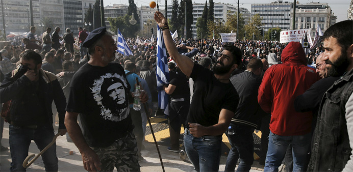 A protesting farmer (C) throws an orange at riot police during clashes in Athens