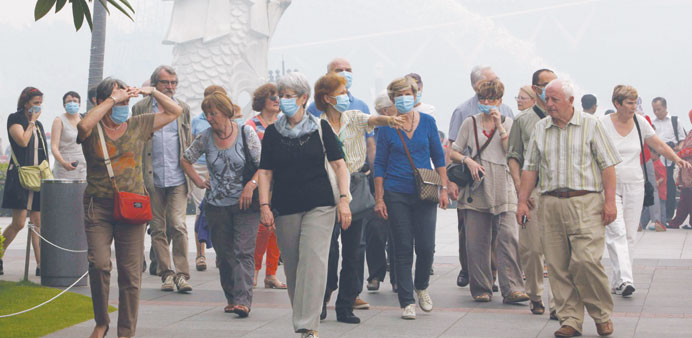 A tour group wearing face masks walk past the Merlion at Marina Bay in Singapore yesterday.